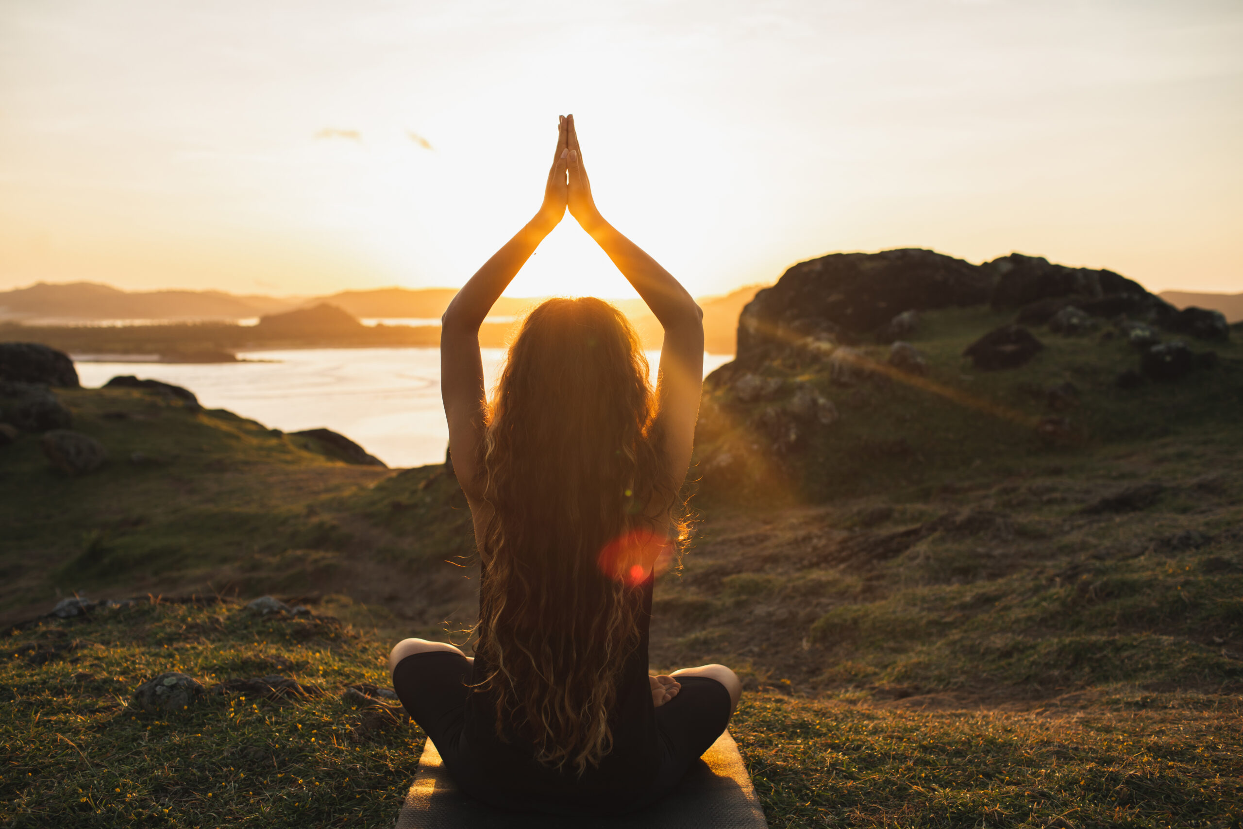 Young woman practicing yoga outdoors. Spiritual harmony, introspection and well-being concept. Landscape background